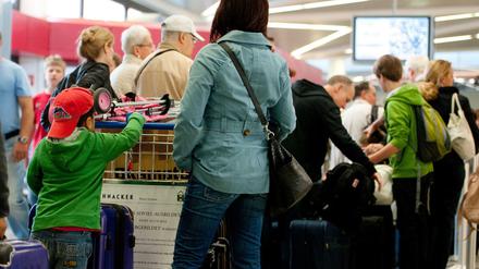 Passagiere warten mit ihrem Gepäck an einem Check-in-Schalter im Flughafen Tegel.