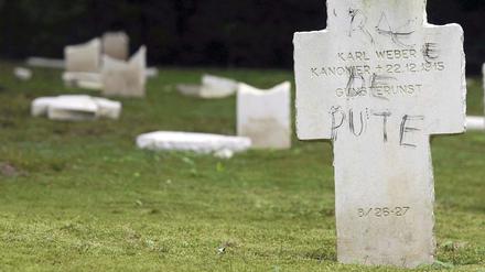 "Hurenrasse" steht auf dem Kreuz für dieses deutsche Soldatengrab. Im Hintergrund umgestoßene und zerstörte Grabkreuze.