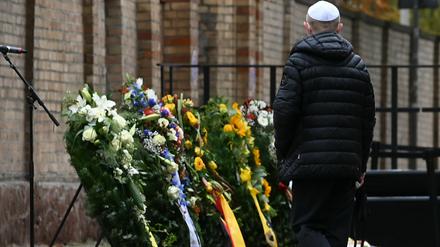 Ein Mitglied der jüdischen Gemeinde steht vor der Synagoge an Gedenkkränzen.
