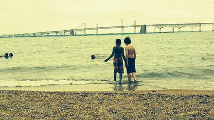 Eine Zufallsbekanntschaft am Strand. Ein schwarzer Junge und ein weißer Junge wagen sich gemeinsam ins kalte Wasser.