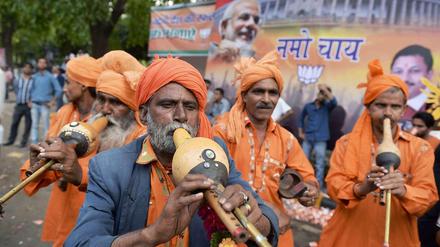 Musiker spielen vor einem Wahlplakat der BJP.