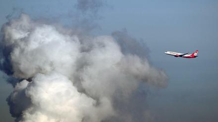 Ein Flugzeug der Airline "Air Berlin" fliegt an einer riesigen Wasserdampfwolke des Heizkraftwerkes Reuter in Siemensstadt vorbei.