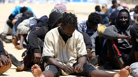  Migranten sitzen auf dem Boden an der Marinebasis in der libyschen Hauptstadt. 