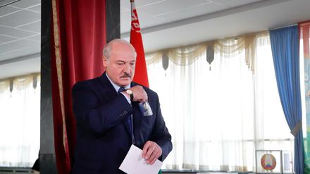 Alexander Lukaschenko, Präsident von Weißrussland, trägt seinen Stimmzettel durch ein Wahllokal während der Präsidentschaftswahlen.