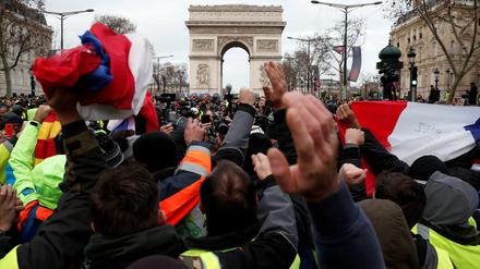 Demonstranten schwenken französische Flaggen vor dem Arc de Triomphe in Paris.
