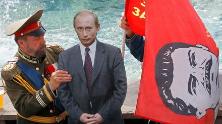 Starke oder schwache Führer machen die Geschichte, glaubt Putin. Hier ein als Zar verkleideter Mann mit einem Pappbild von Putin und Fahren mit Stalins Konterfei (Archivbild). 