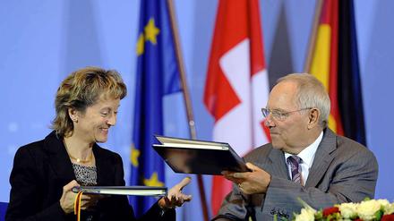 Bundesfinanzminister Wolfgang Schäuble (CDU) und die Schweizer Bundesrätin Eveline Widmer-Schlumpf tauschen im Finanzministerium in Berlin nach der Unterzeichnung eines Steuerabkommens die Mappen aus.