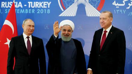 Der türkische Präsident Recep Tayyip Erdogan (r.) , der iranische Präsident Hassan Rouhani (M.) und der russische Präsident Wladimir Putin winken ins Publikum. 