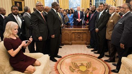 Kellyanne Conway, Beraterin von US-Präsident Donald Trump, beschäftigt sich am Montag mit ihrem Handy, während Donald Trump mit Vertretern amerikanischer Universitäten spricht. Das Foto wurde im Oval Office aufgenommen.