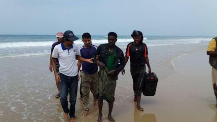 Mitarbeiter der Internationalen Organisation für Migration aus dem Jemen helfen einem Überlebenden des Bootsunglücks.