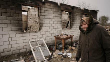 Eine Frau geht an einem Haus vorbei, das während der Besetzung ihres Dorfes durch russische Truppen in Andrijiwka, Ukraine, zerstört wurde.