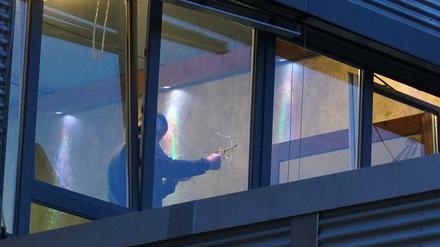 Ein Ermittler untersucht ein Einschussloch in einer Fensterscheibe. Der oder die Täter hätten mit einer unbekannten Waffe noch ein weiteres Fenster in dem Gebäudekomplex beschossen.