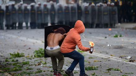 Demonstranten werfen einen Brandsatz auf Polizisten bei Protesten in Venezuela.