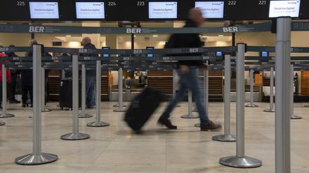 Ein Reisender geht mit einem Koffer zu einem Check-in-Schalter von Eurowings.