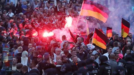 Demonstranten der rechten Szene zünden am 27. August 2018 in Chemnitz Pyrotechnik und schwenken Deutschlandfahnen. Nach einem Streit war in der Nacht zu Sonntag in der Innenstadt von Chemnitz ein 35-jähriger Mann erstochen worden. Die Tat war Anlass für spontane Demonstrationen, bei denen es auch zu Jagdszenen und Gewaltausbrüchen kam.