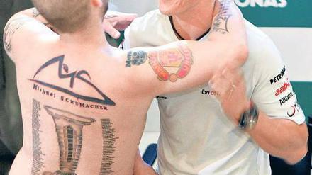 Schumi auf der Haut. Michael Schumacher wird in Malaysia von einem Fan umarmt, der seiner Liebe zu seinem Idol mit Tattoos Ausdruck verleiht. Foto: Reuters