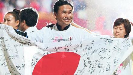 Fahnenkleid. Japans Trainer Norio Sasaki zeigt feiernd Flagge. 