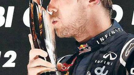 Kuss zum Schluss. Vettel liebkost den Lohn seiner Mühen. Foto: dapd