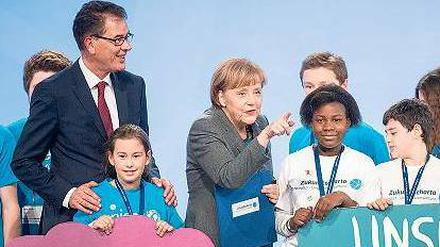 Blauer Planet, blaue Mappe. Entwicklungsminister Gerd Müller überreicht Kanzlerin Angela Merkel die „Charta“.