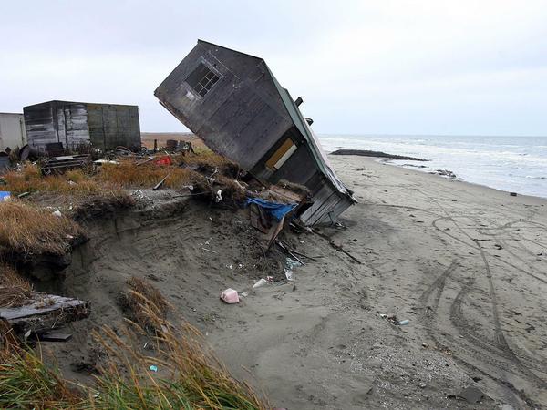 Ein Holzhaus am Meer ist von der Steilküste auf den Strand gestürzt.