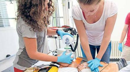Zwei Medizinstudentinnen üben an einer Puppe, einen Patienten wiederzubeleben.