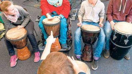 Vier Schüler, eine davon mit einer Behinderung, spielen auf Trommeln.