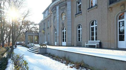 Die Fassade einer Villa im Gegenlicht fotografiert, davor schneebedeckte Gartenanlagen.