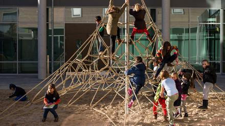 Grundschulkinder klettern auf dem Schulhof in einer Kletterspinne.