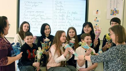 Eine Lehrerin begrüßt ukranische Schülerinnen mit kleinen Schultüten.