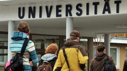 Eine Gruppe von Studierenden geht auf das Hauptgebäude einer Universität zu.